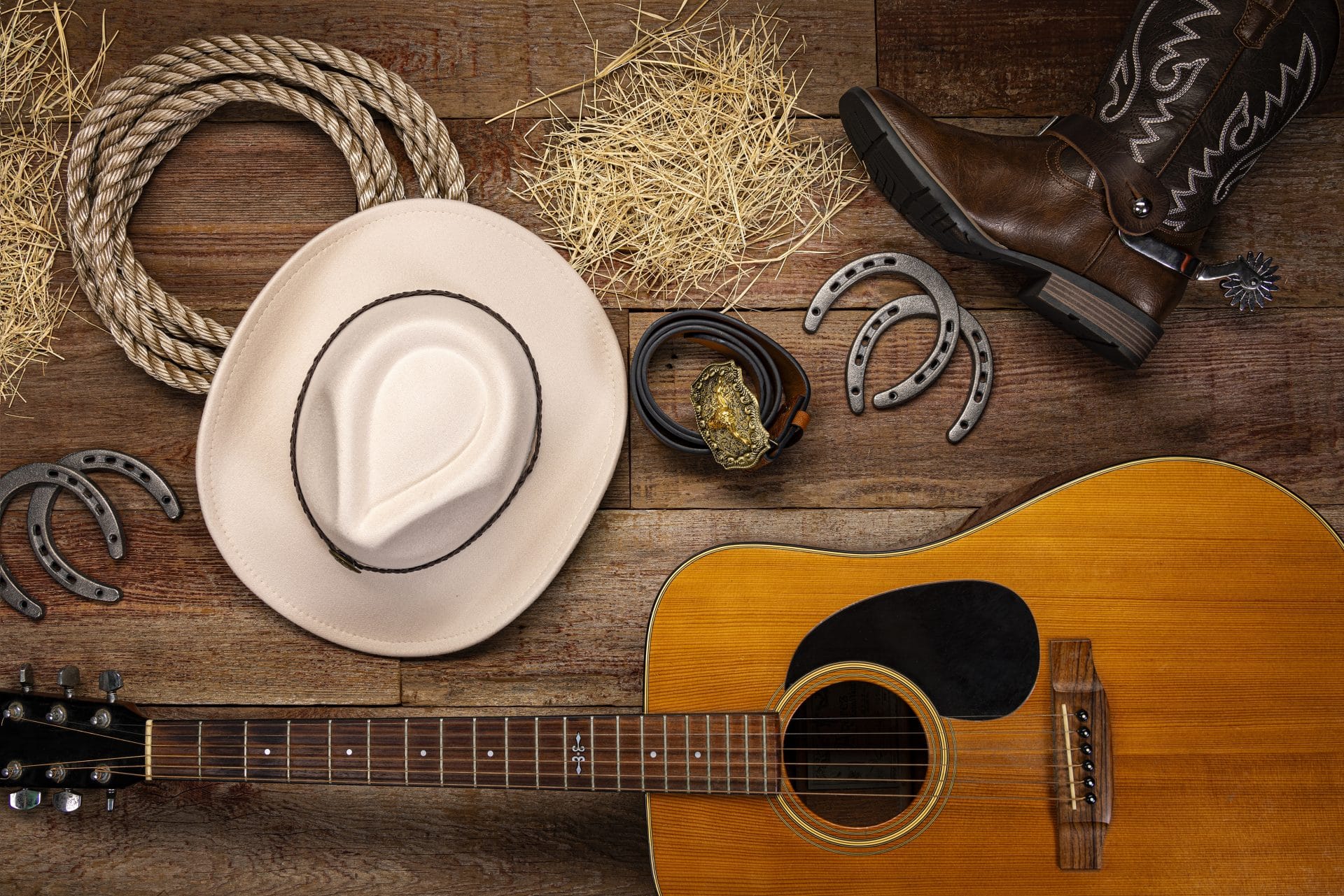Guitar, cowboy hat, and boots on wooden floor at Hotel LaBonte.