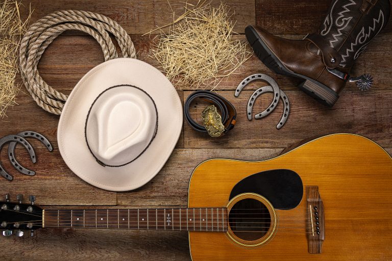 Guitar, cowboy hat, and boots on wooden floor at Hotel LaBonte.